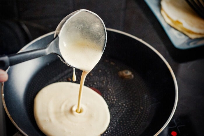 pouring pancakes into a pan