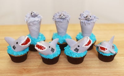 Chocolate cupcakes with blue frosting and smiling shark heads on top