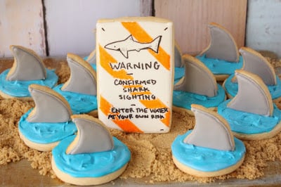 Sugar cookies with shark fins on them on top of brown sugar "sand"