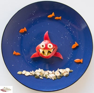 Various snack food items on a plate creating an underwater scene with a shark