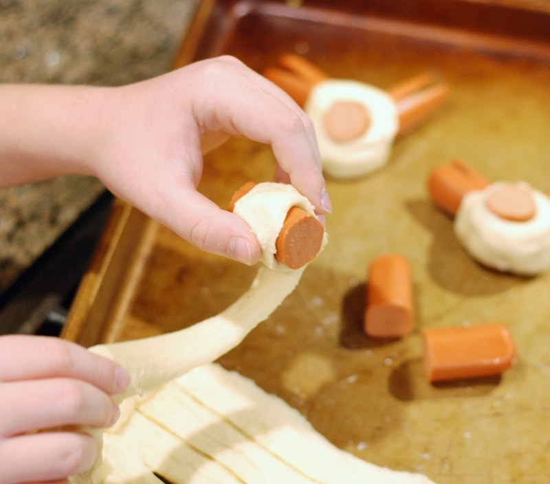 wrapping a piece of a hot dog in dough