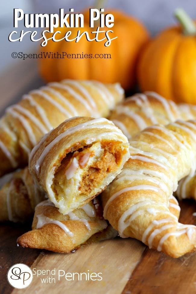 A plate of Pumpkin Pie Crescents, with one crescent broken open to show the filling.