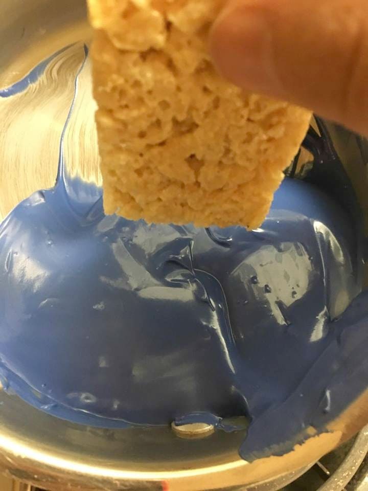 Dipping Rice Krispie Treat into Candy Melts for Minion Treats