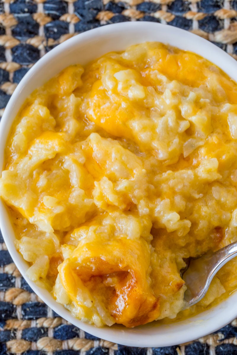 Hash brown casserole in a white bowl with a fork taking some out