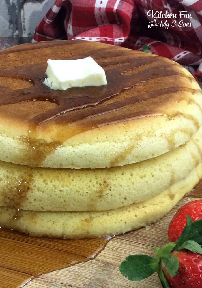 A stack of puffy pancakes topped with butter and syrup