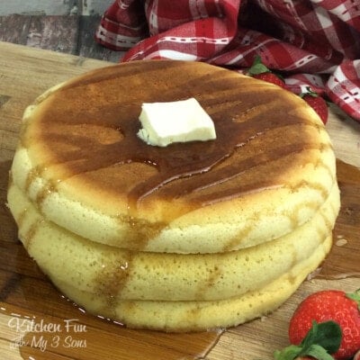 A stack of puffy pancakes on a wooden cutting board