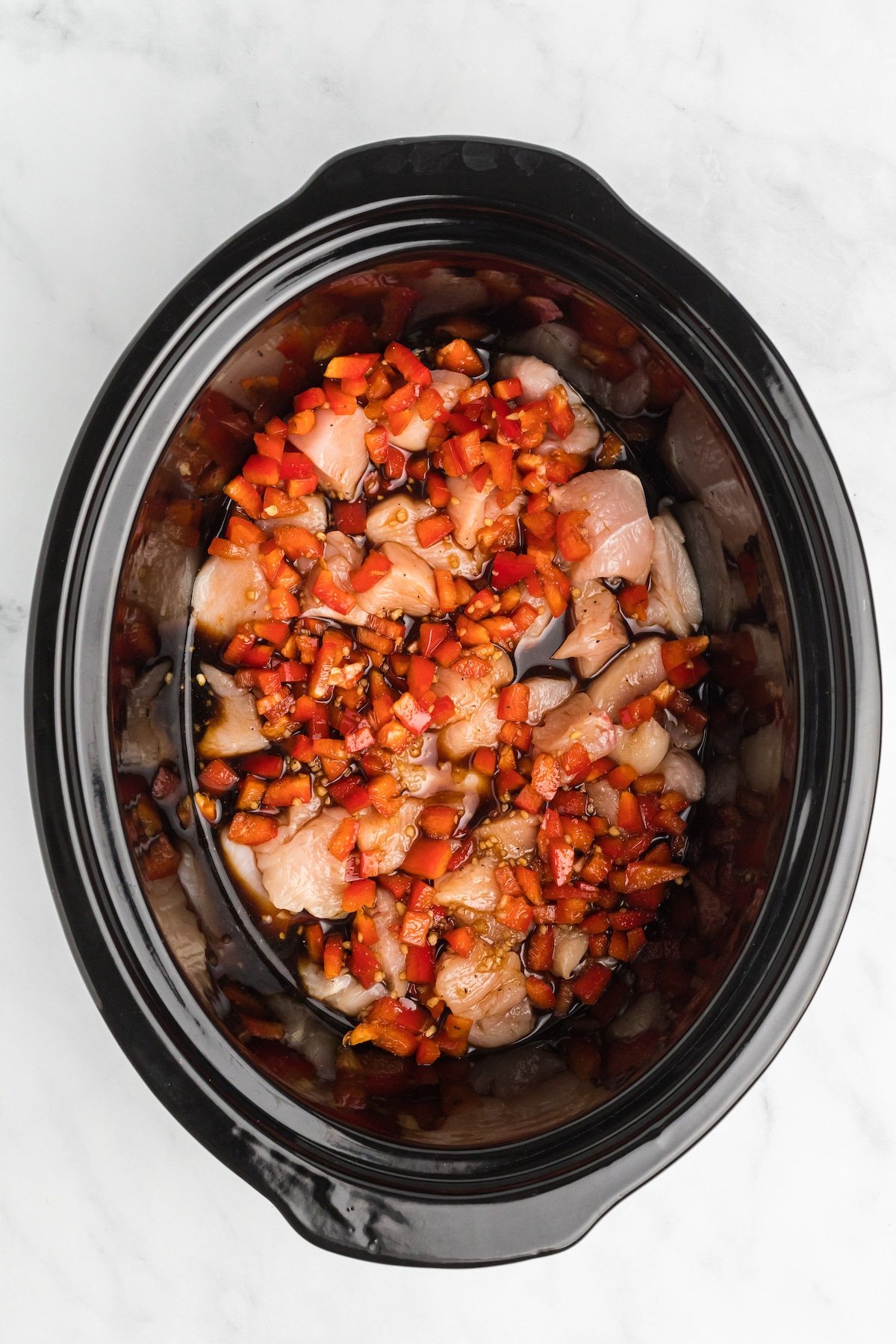 Chunks of chicken breast topped with teriyaki sauce in the slow cooker