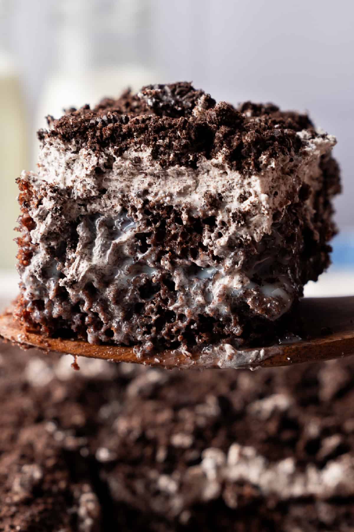 Oreo Poke Cake slice being lifted with a spatula