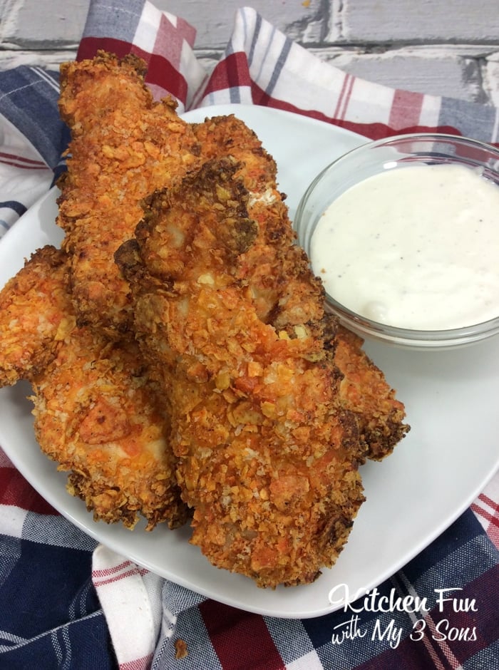 Doritos air fryer chicken tenders on a plate next to white dipping sauce.