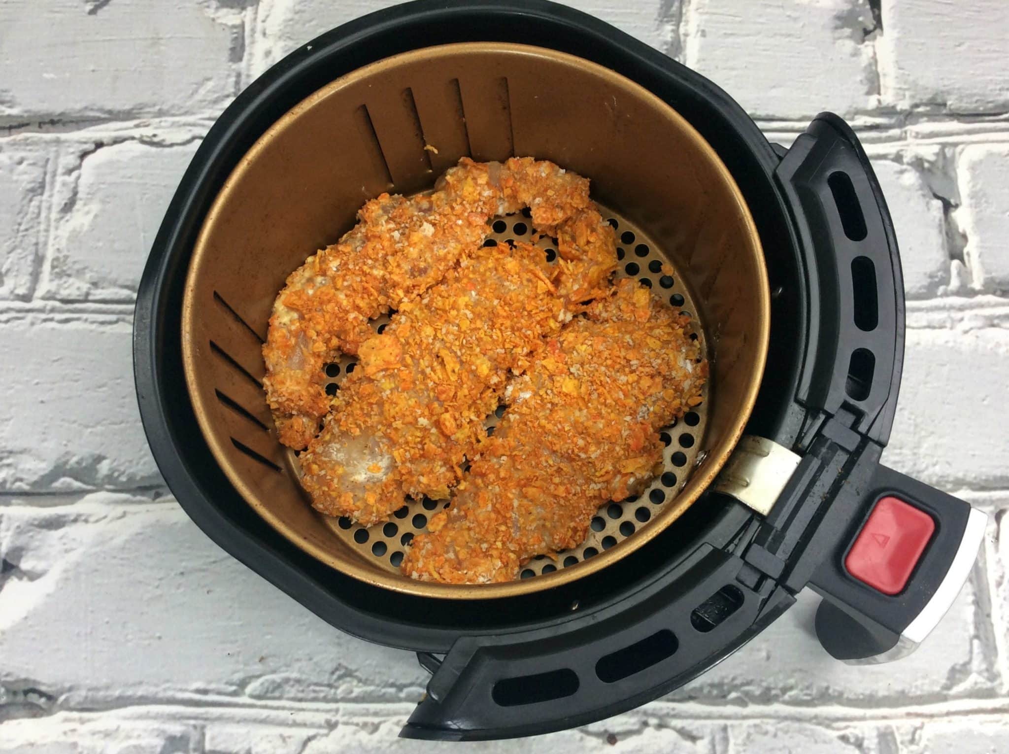 Doritos chicken tenders inside the basket of an air fryer.