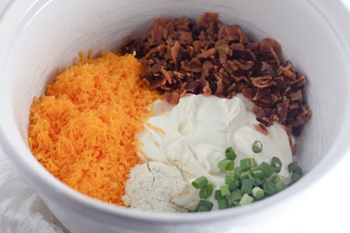 cheese, sour cream, ranch, bacon and green onions in a bowl
