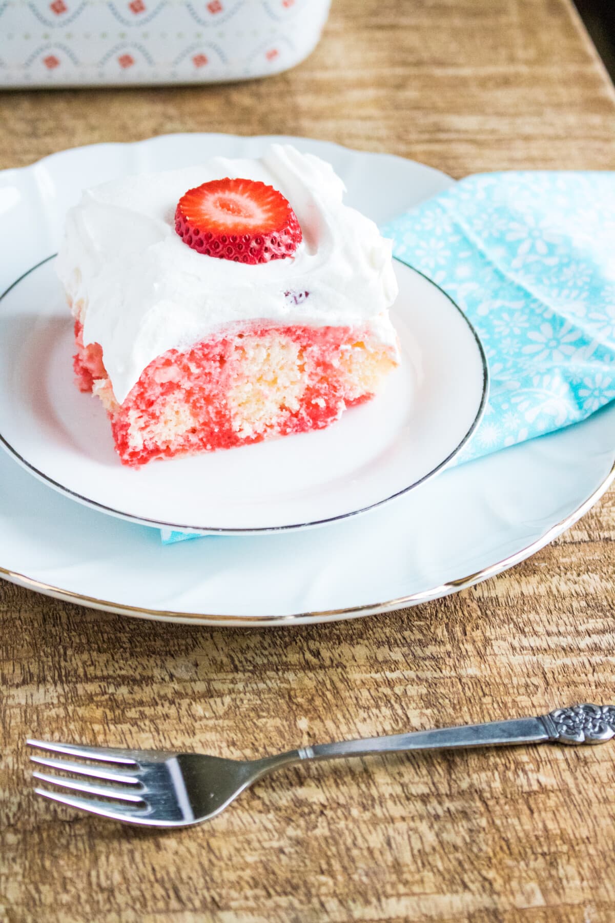 Strawberry Poke Cake with whipped cream on top.