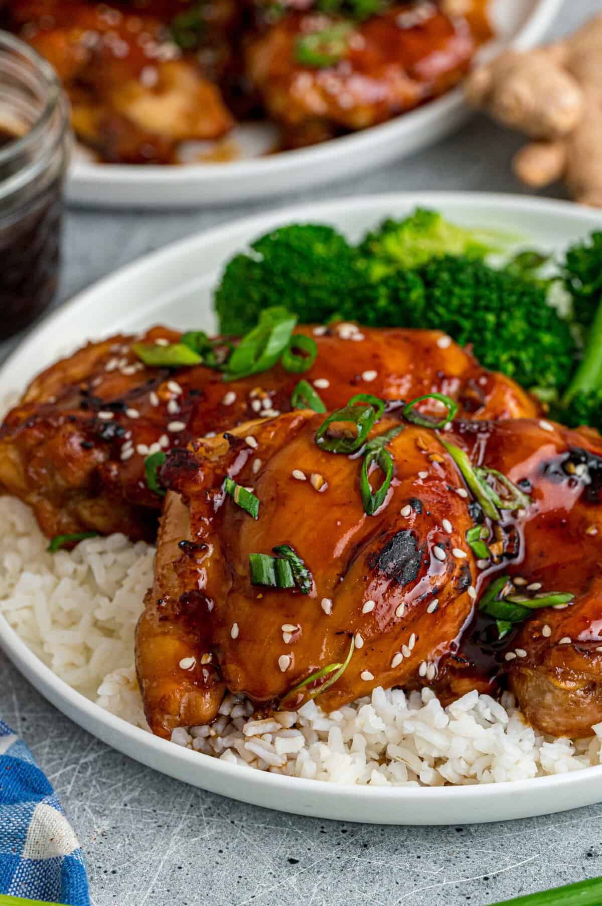 Tender, juicy chicken is baked in a sweet and savory glaze in this Baked Teriyaki Chicken Thighs recipe. Quick & easy! Baked teriyaki chicken thighs on a plate with rice and broccoli