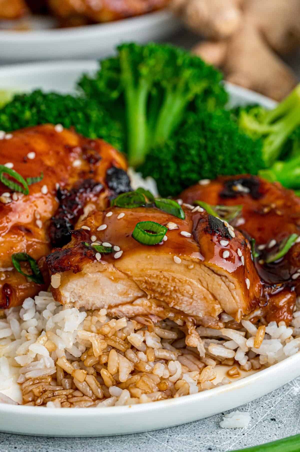 Tender, juicy chicken is baked in a sweet and savory glaze in this Baked Teriyaki Chicken Thighs recipe. Quick & easy! Baked teriyaki chicken thighs on a plate with a bite missing to show the juicy inside