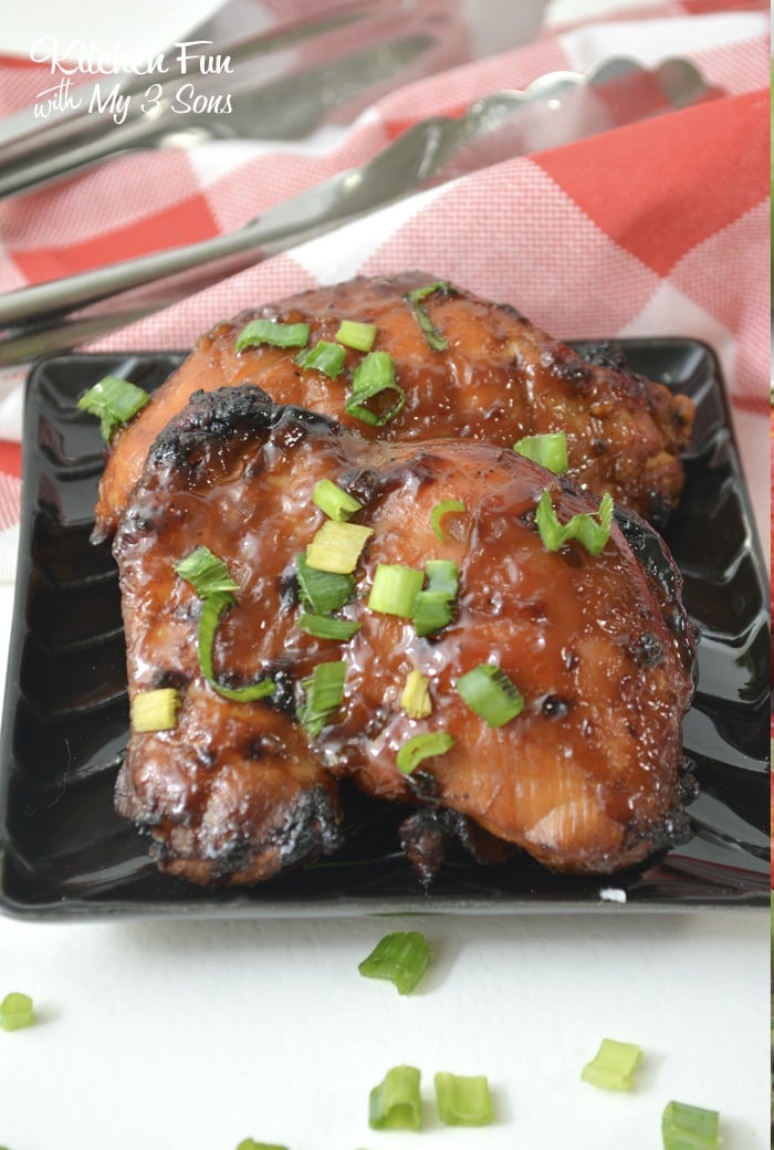 Two baked chicken thighs on a black plate