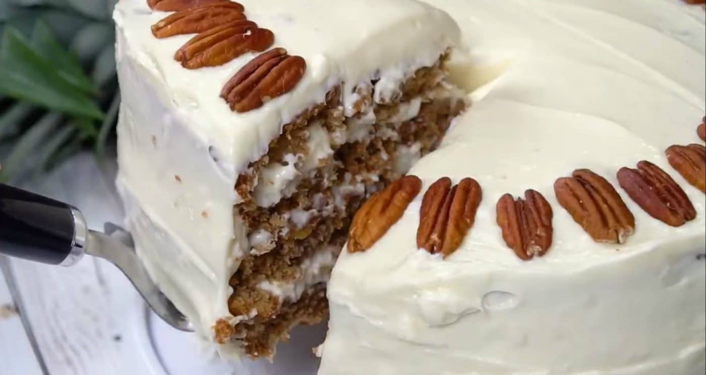 A slice of Hummingbird Cake being lifted away from the rest of the cake.