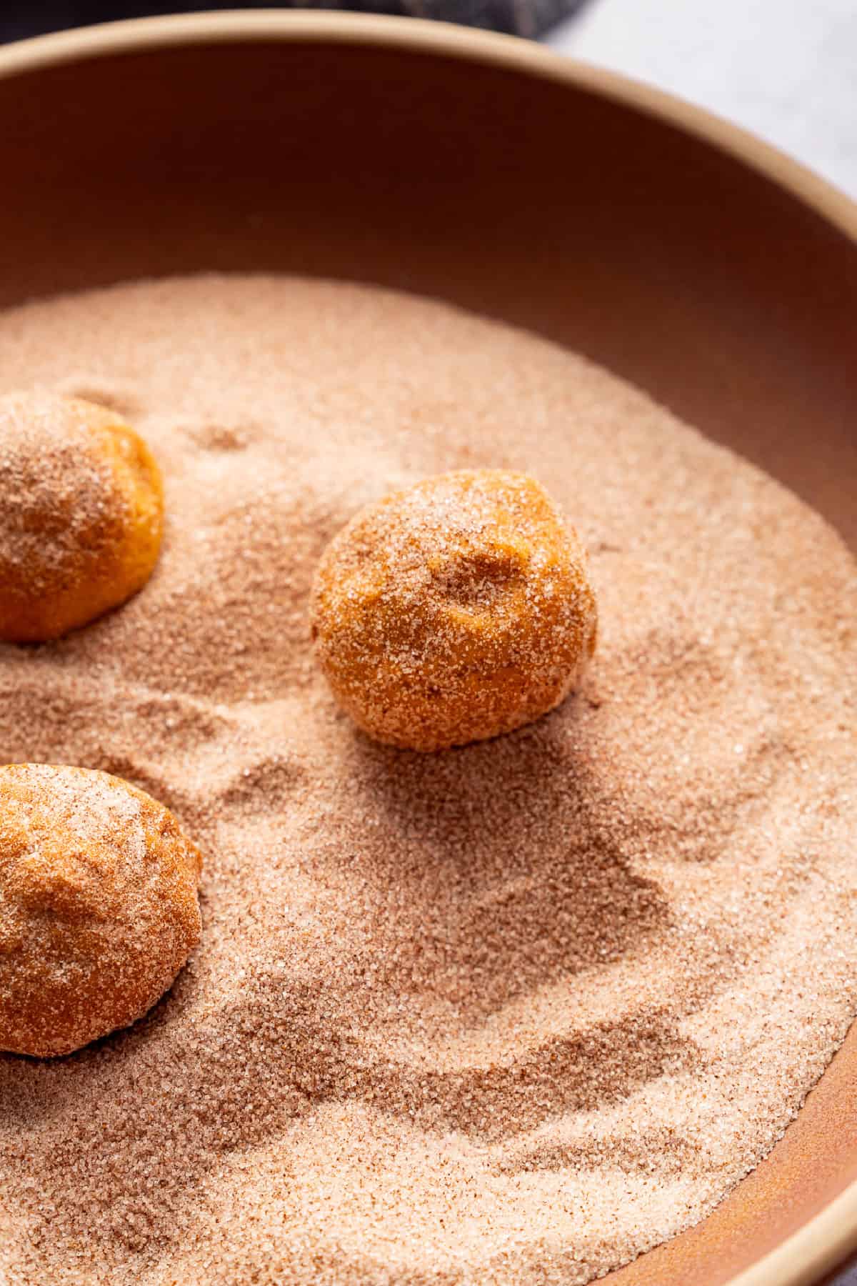 rolling the cookie dough balls in to cinnamon sugar