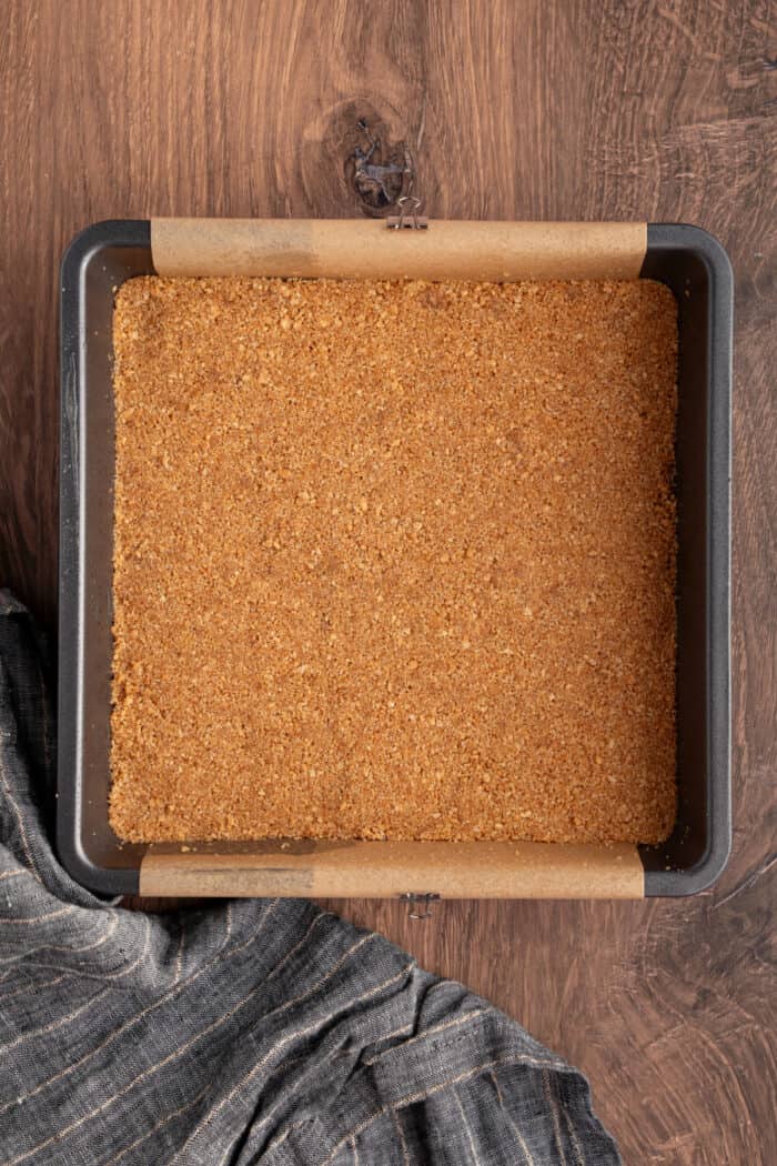 These Pumpkin Cheesecake Bars is the ultimate Fall dessert that starts with a cinnamon graham cracker crust that's layered with creamy vanilla cheesecake and then topped with spiced pumpkin cheesecake. graham cracker crust in a pan