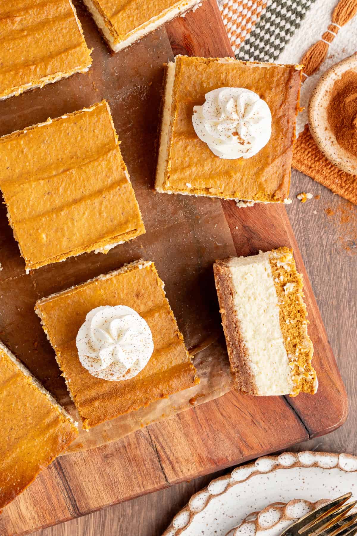 These Pumpkin Cheesecake Bars is the ultimate Fall dessert that starts with a cinnamon graham cracker crust that's layered with creamy vanilla cheesecake and then topped with spiced pumpkin cheesecake. pumpkin cheesecake bars cut into squares