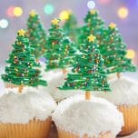 A batch of vanilla cupcakes with chocolate pretzel Christmas tree treats on top