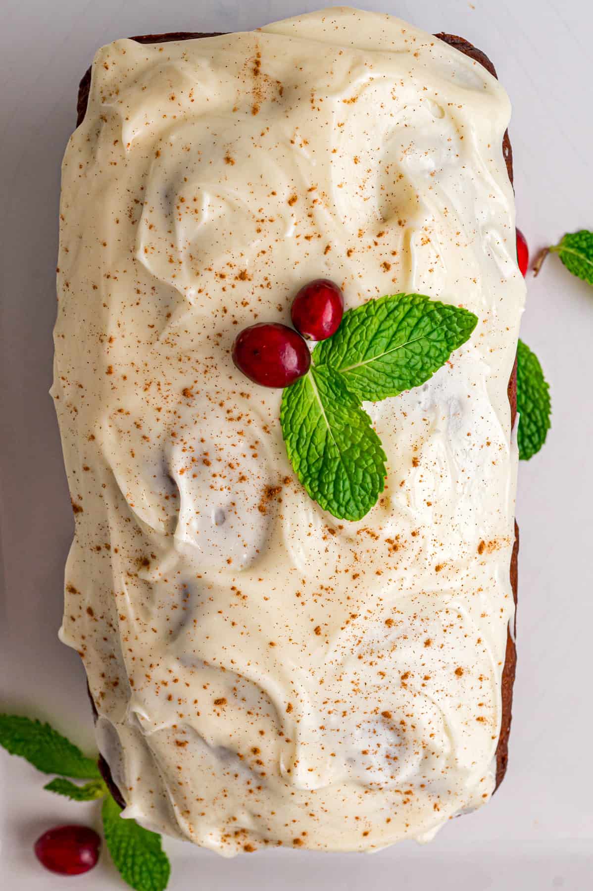 Warmly spiced, moist bread is topped with tangy cream cheese frosting in this Gingerbread Loaf recipe, inspired by Starbucks. Overhead view of frosted gingerbread loaf
