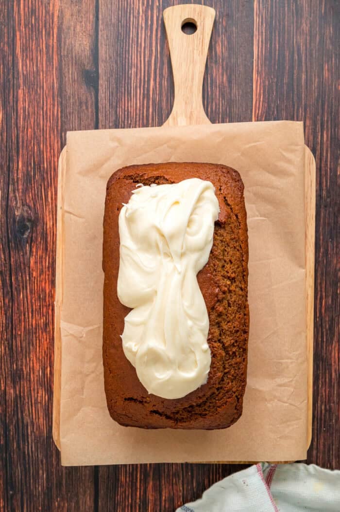 Warmly spiced, moist bread is topped with tangy cream cheese frosting in this Gingerbread Loaf recipe, inspired by Starbucks. Spreading cream cheese frosting on gingerbread loaf