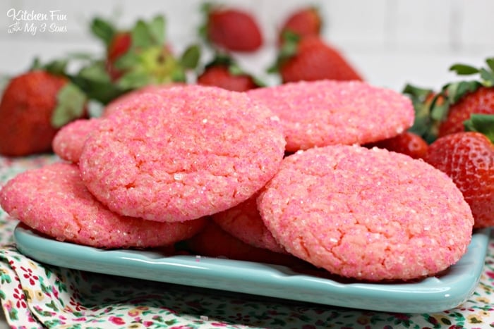 Strawberry champagne cookies on a blue plate with fresh berries in the background.