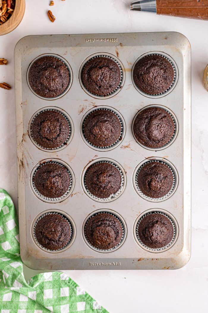 Chocolate cupcakes are filled with a sweet coconut pecan mixture and topped with chocolate buttercream in these German Chocolate Cupcakes. Chocolate cupcakes in a cupcake tin