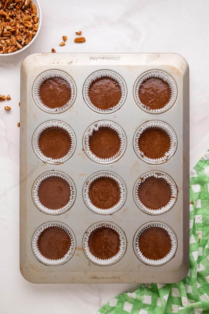 Chocolate cupcakes are filled with a sweet coconut pecan mixture and topped with chocolate buttercream in these German Chocolate Cupcakes. Cupcake liners filled with chocolate cupcake batter