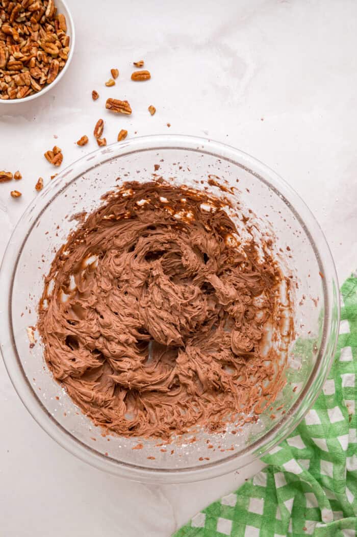 Chocolate cupcakes are filled with a sweet coconut pecan mixture and topped with chocolate buttercream in these German Chocolate Cupcakes. Chocolate buttercream in a bowl.