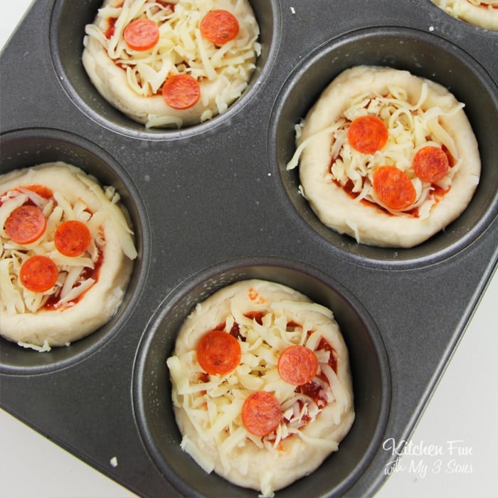 An overhead shot of a cupcake tin full of unbaked pepperoni pizza bites