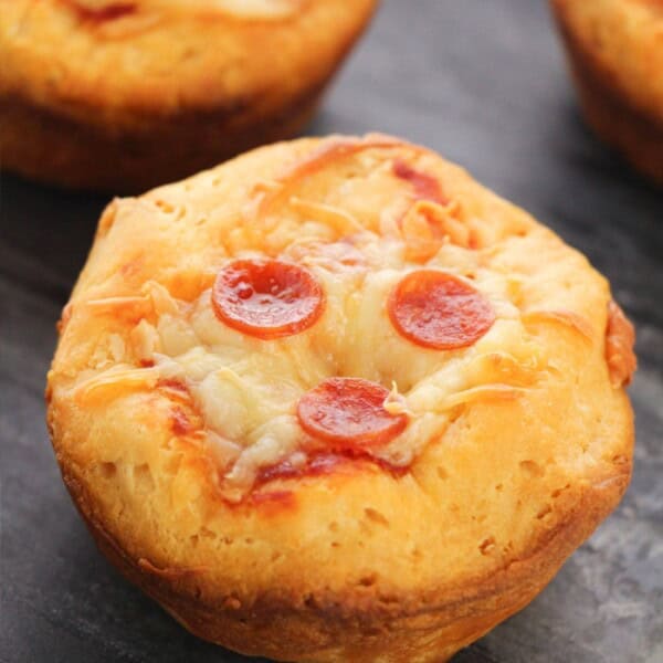 A close-up shot of a pepperoni pizza bite sitting on top of a small pizza stone