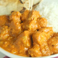 Overhead view of butter chicken on a plate with rice and naan