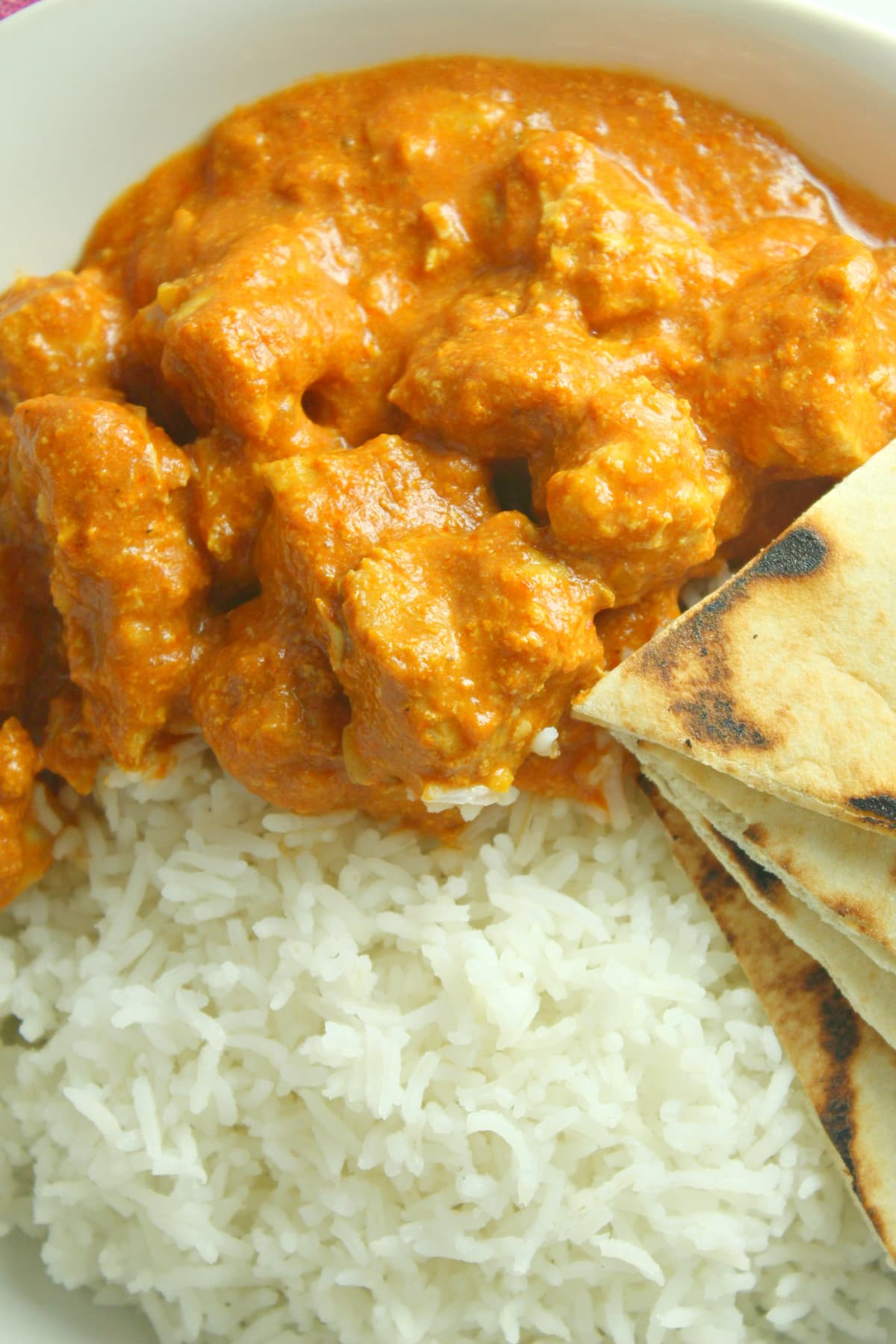 Overhead view of butter chicken with rice and naan