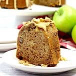 A slice of Caramel Apple Bundt Cake on a white plate with Granny Smith apples and the rest of the cake in the background.