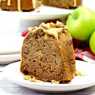 A slice of Caramel Apple Bundt Cake on a white plate with Granny Smith apples and the rest of the cake in the background.