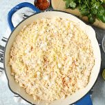 Overhead view of skillet Mexican corn dip in a blue skillet, surrounded by dip ingredients.