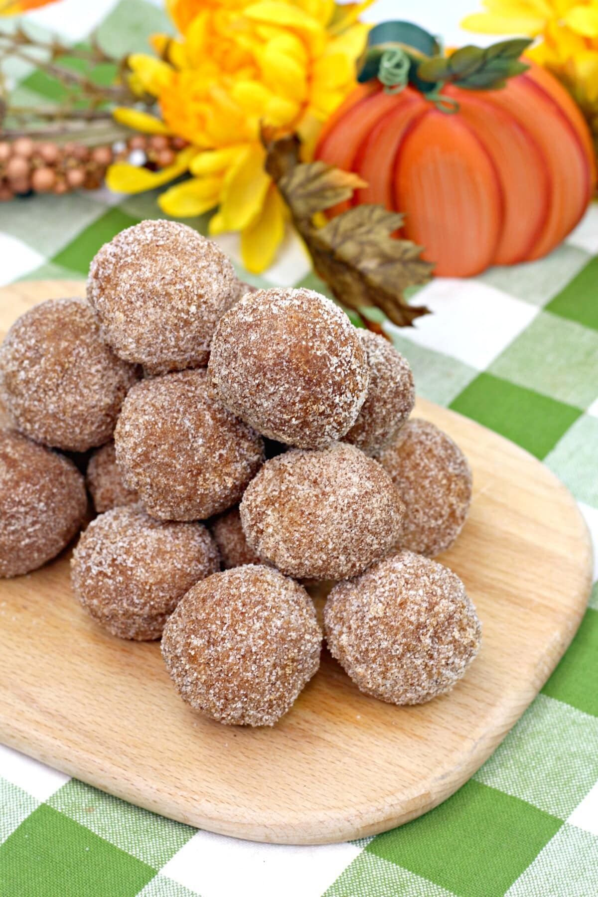 Pumpkin Donut Holes with Fall decorations in the back.