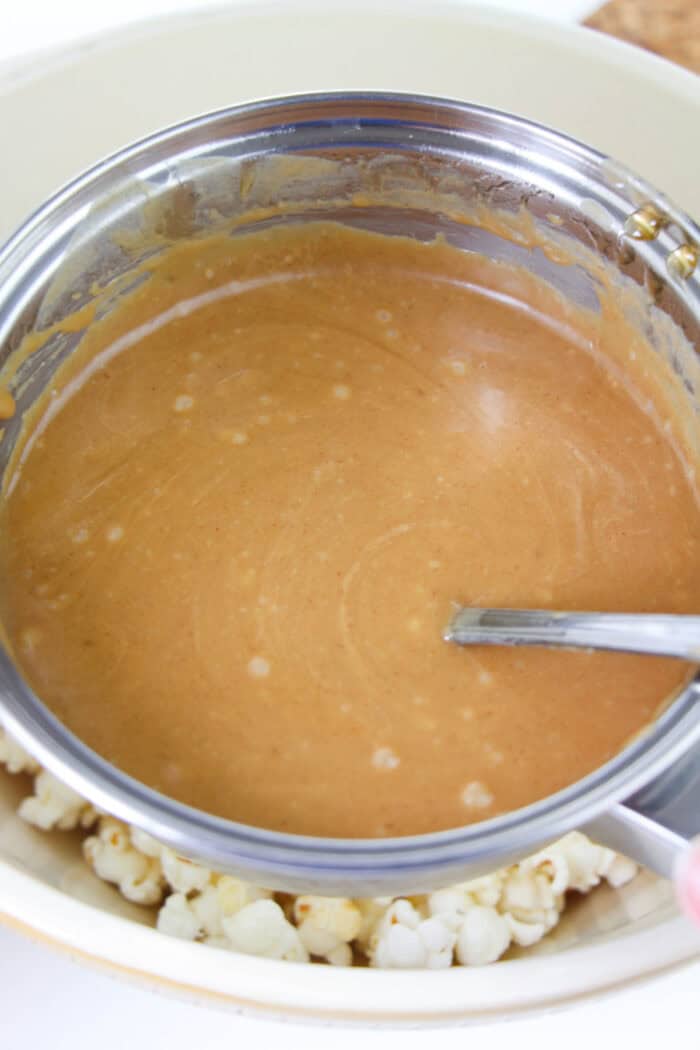 This easy Peanut Butter Popcorn recipe uses just 4-ingredients and is the most delicious snack for peanut butter lovers! peanut butter sauce in a sauce pan