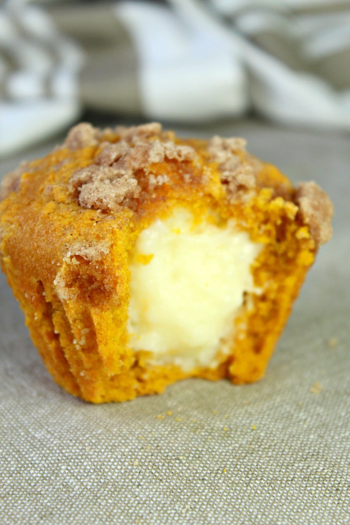 a cut open pumpkin cheesecake muffin showing the filling