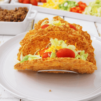 Keto taco shells filled with veggie sand meat sitting on a white plate