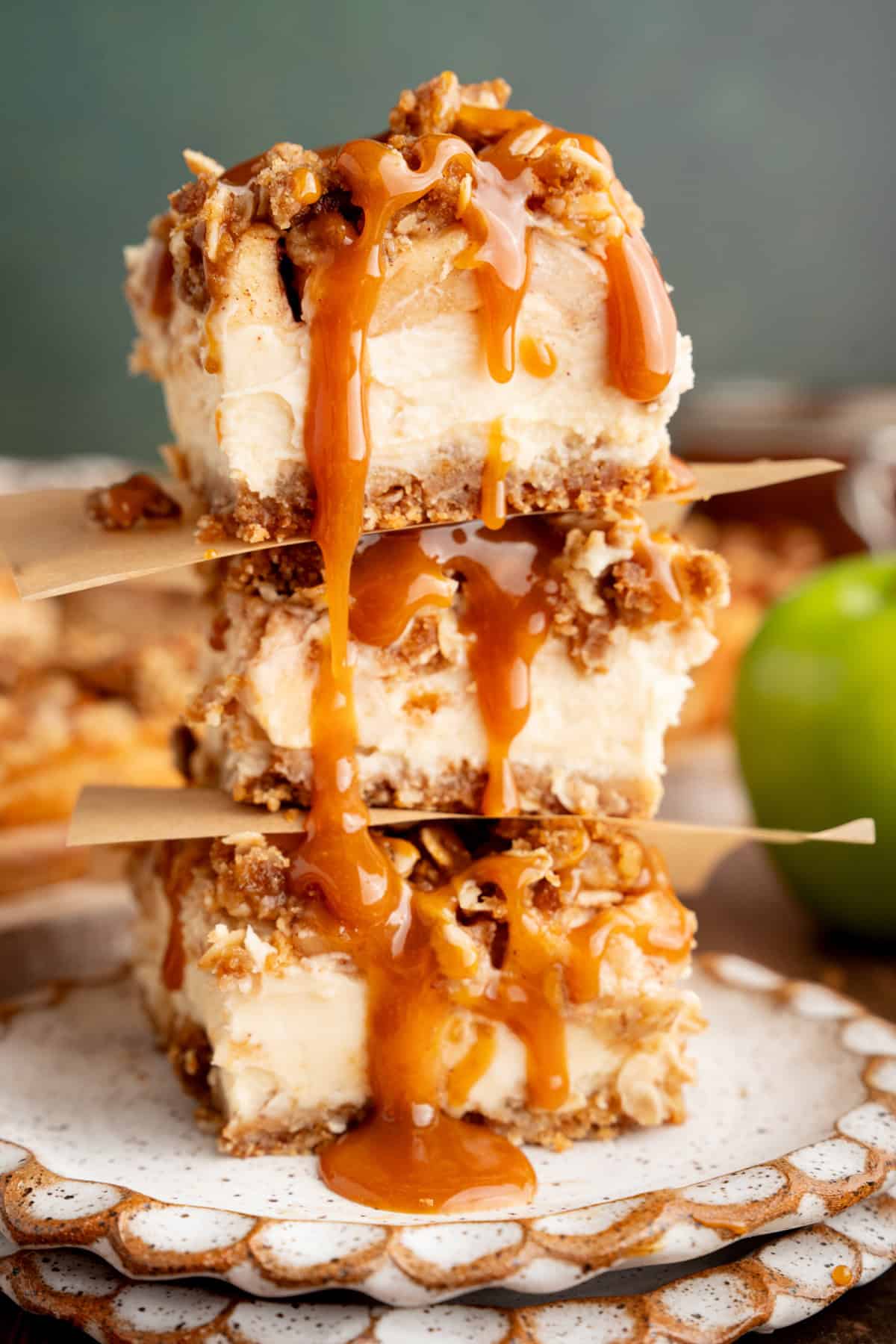 These Caramel Apple Cheesecake Bars combine creamy caramel cheesecake with cinnamon-spiced apples and a buttery oat crumble. Stacked Caramel Apple Cheesecake Bars.