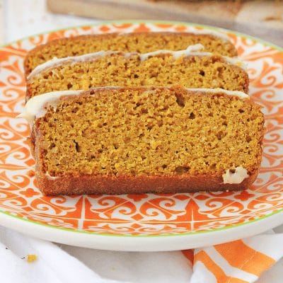 Slices of gluten free pumpkin bread on an orange and white plate.
