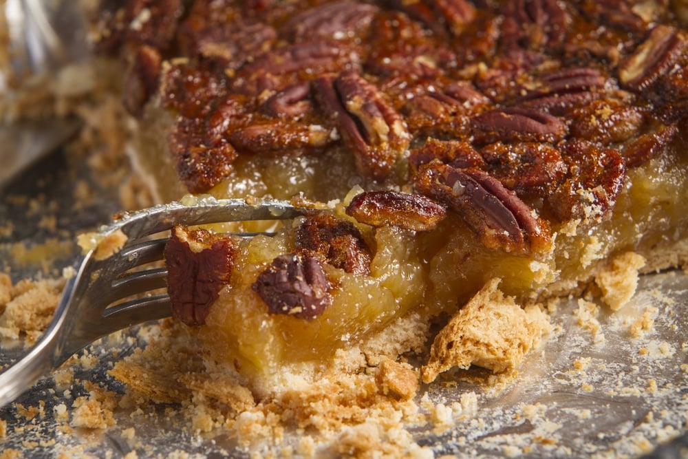 A fork digging into a slice of homemade pecan pie