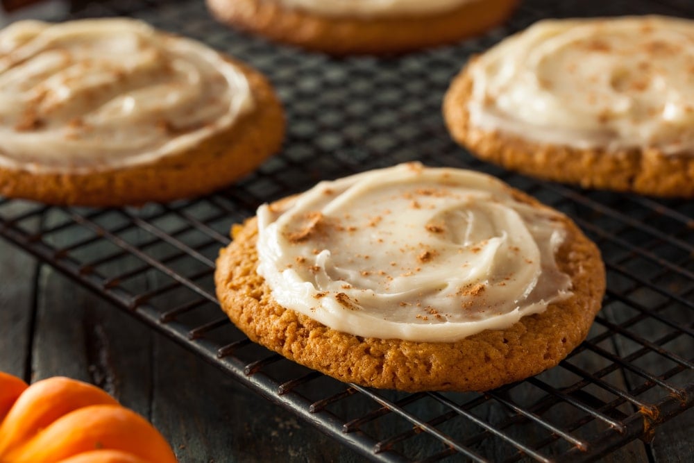 Soft cream cheese Frosted Pumpkin Cookies on a wire rack
