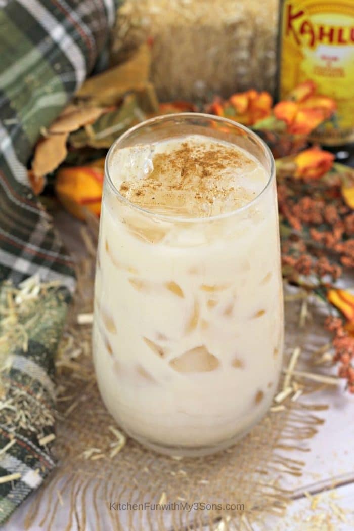 A pumpkin white Russian in a tall glass with fall decorations in the background