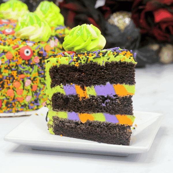 A slice of monster cake sitting on a white square saucer