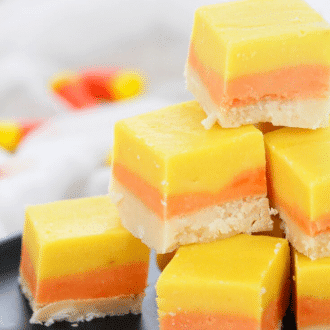 A stack of candy corn layered white chocolate fudge on a black plate