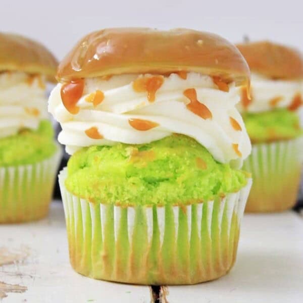 Caramel apple cupcakes in a row on a white wooden surface