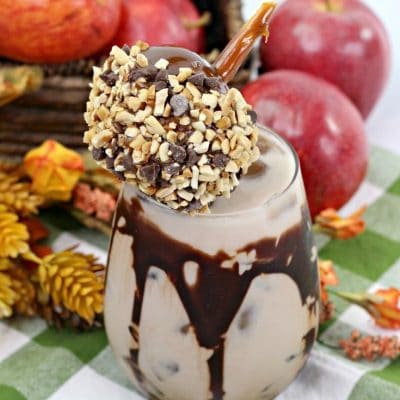 Overhead picture of a chocolate caramel apple cocktail topped with a small caramel apple covered in nuts